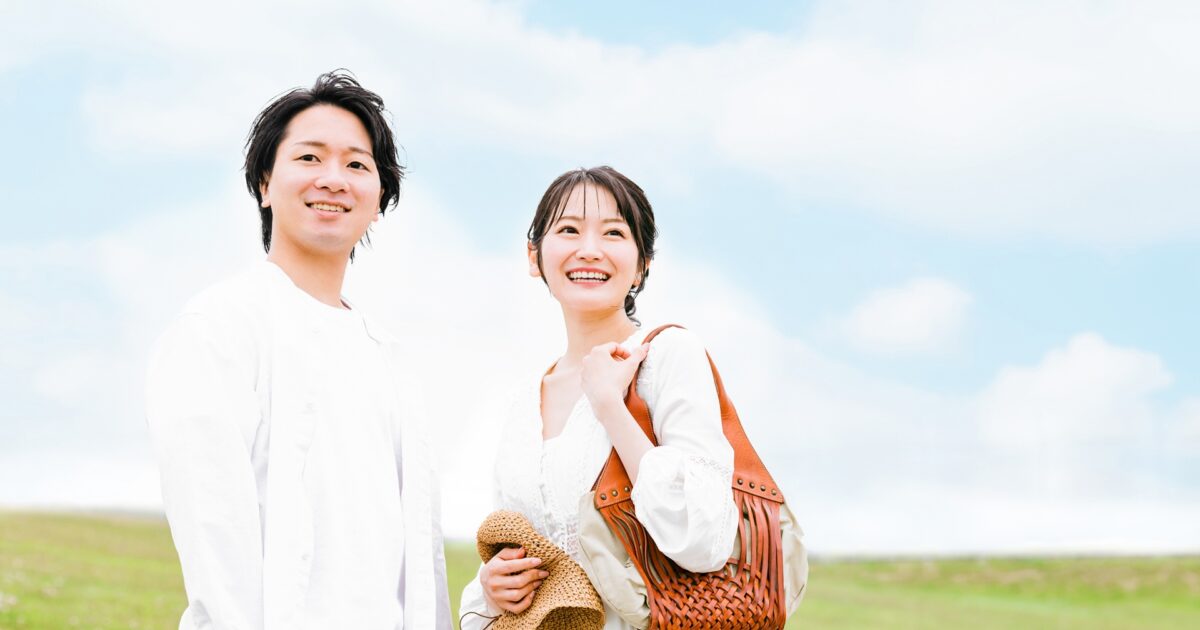 青空の下で仲良く並ぶ白い服のカップル