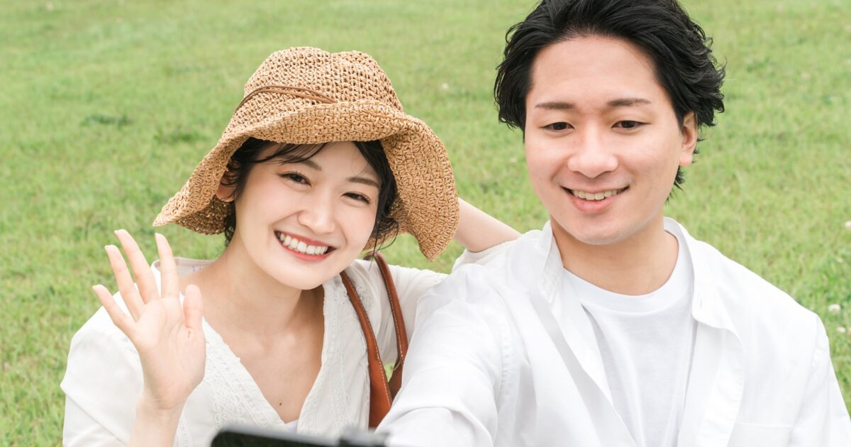 スマートフォンで自撮りを楽しむ帽子姿のカップル