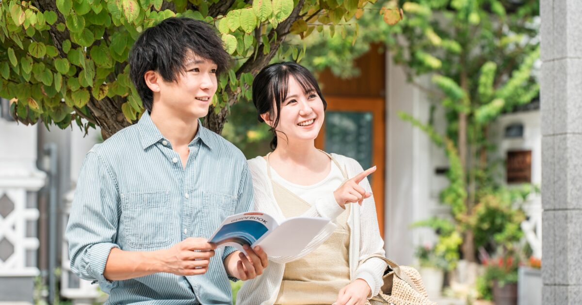 観光ガイドブックを見ながら笑顔で話すカップル