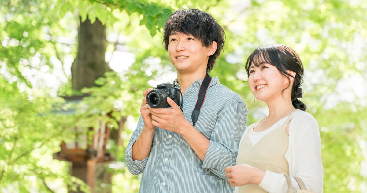 自然の中でカメラを持ちながら景色を楽しむカップル