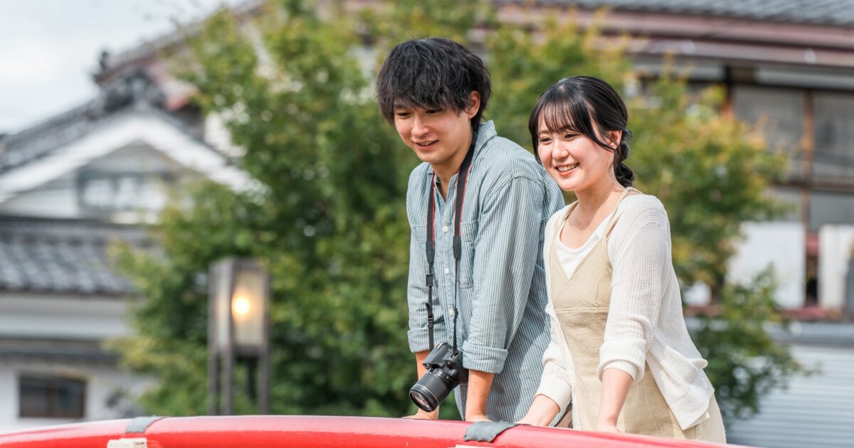 赤い橋の上で景色を眺めながら微笑むカップル