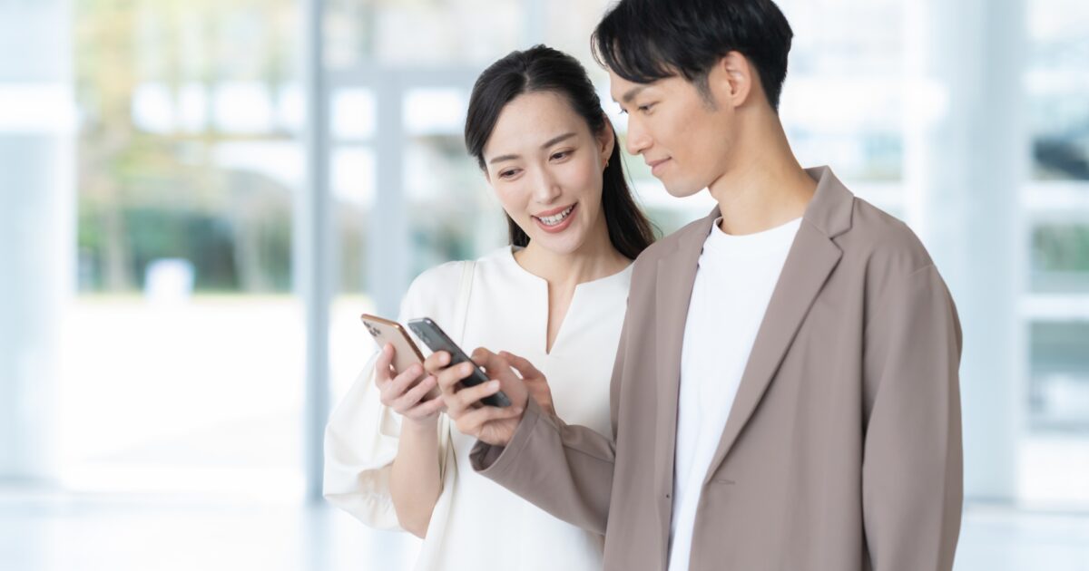 スマートフォンを一緒に見ながら笑顔を交わすカップル