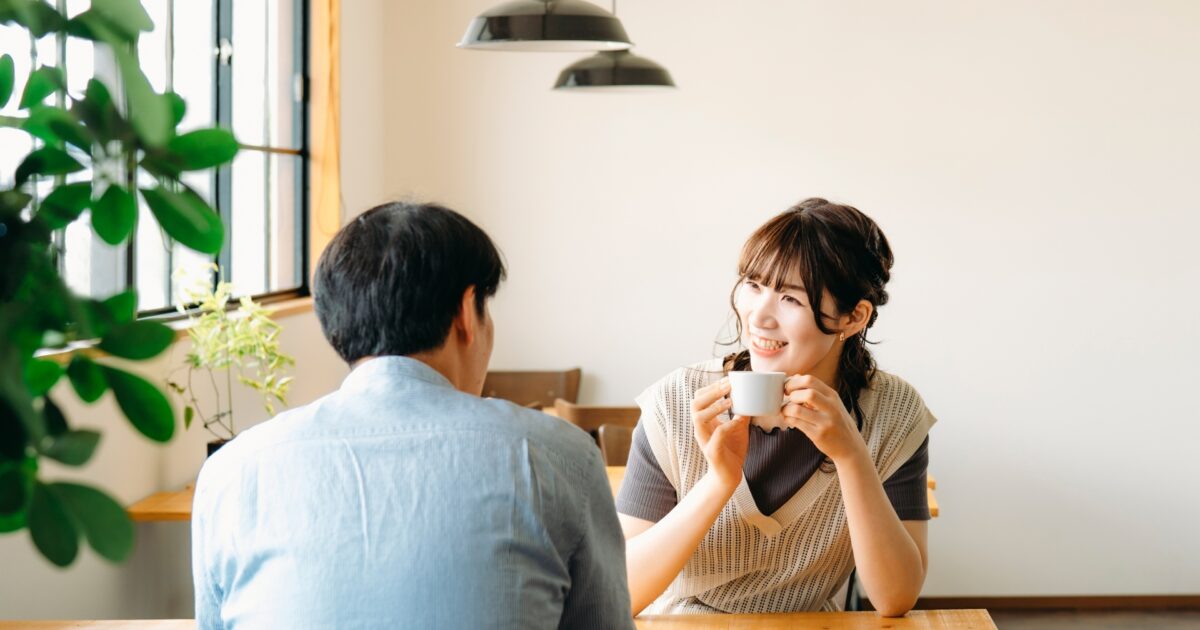 カフェでコーヒーを飲みながら笑い合う男女