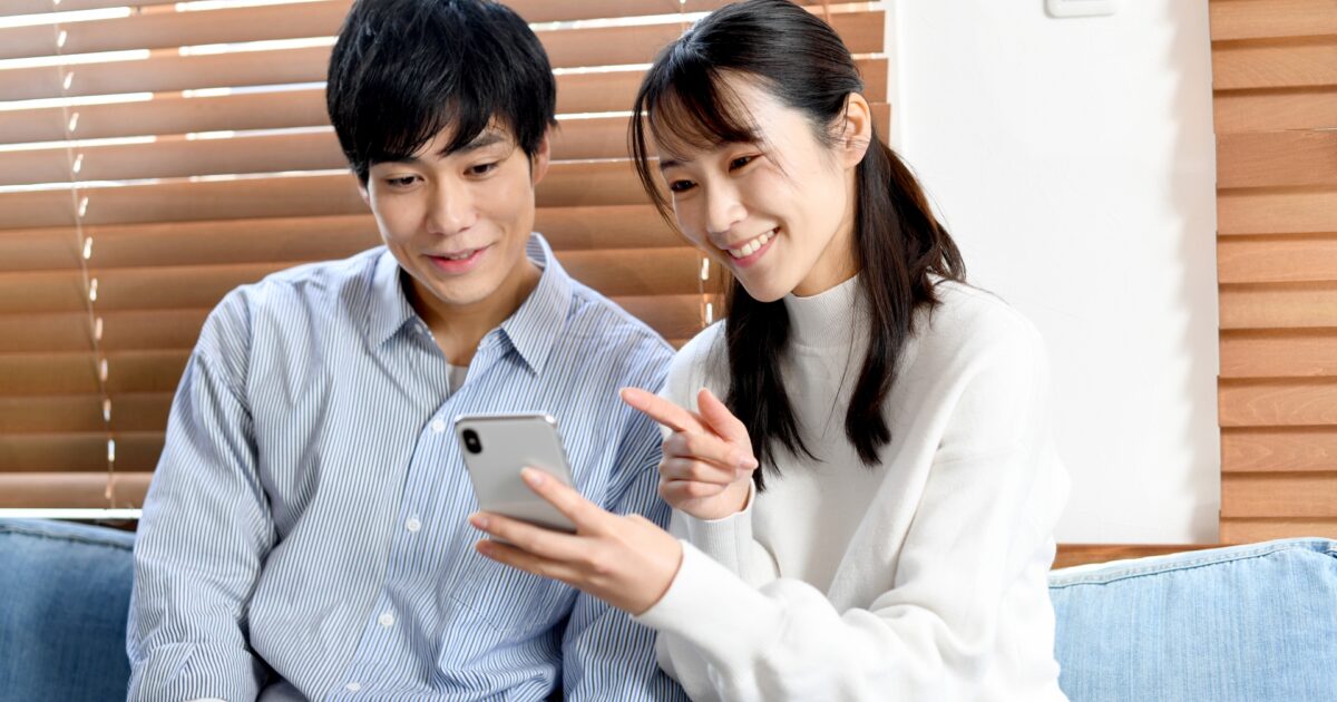 スマートフォンの画面を一緒に見る仲良しカップル
