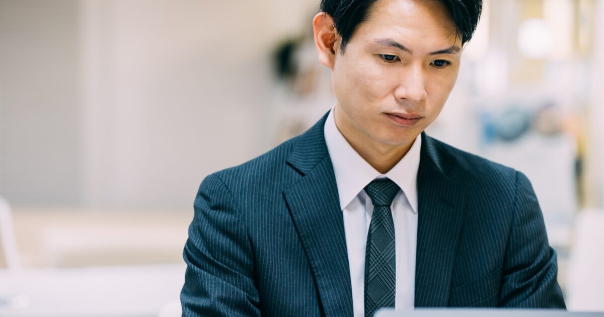 真剣な表情でパソコン作業をするスーツ姿の男性