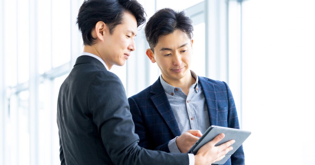 タブレットを見ながら打ち合わせをする男性二人